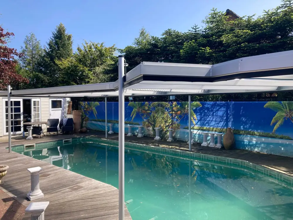 Sechseckbecken auf einem Holzdeck direkt am Wohnhaus, darüber eine flache Überdachung