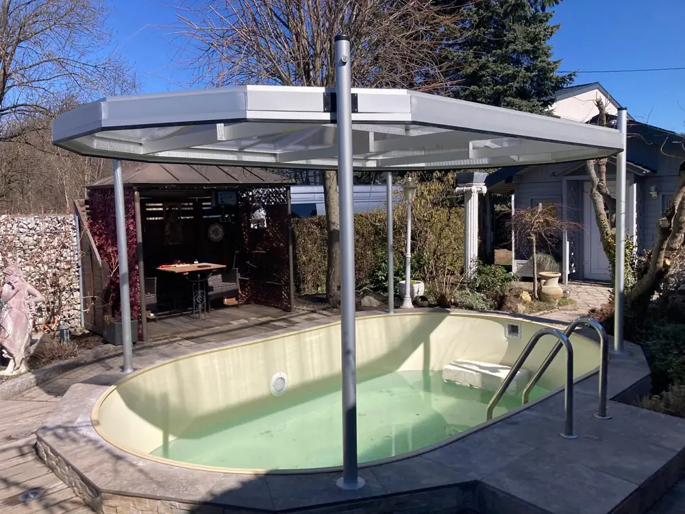 Ovalbecken unter einer an das Haus angebauten Überdachung