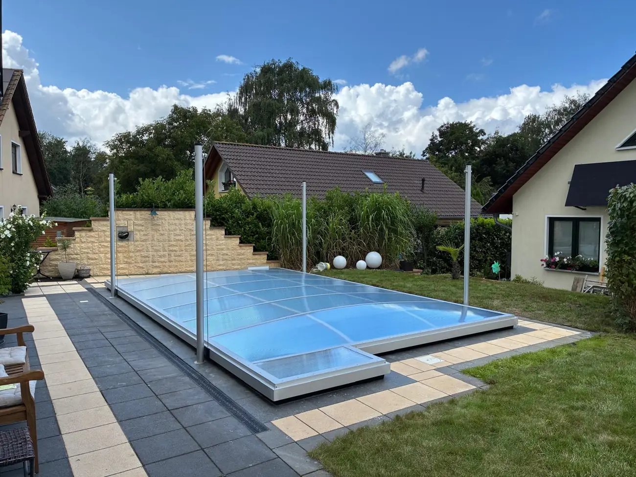 Geschlossene Poolüberdachung über einem Rechteckbecken vor einem Wohnhaus